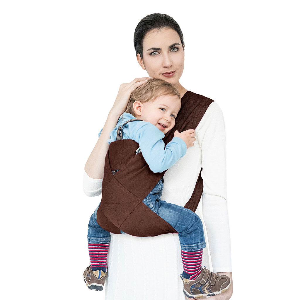 Portabebè Mhug Avana colore Tabacco si indossa in un solo gesto come una T-shirt indossato da modella con bambino di circa quattordici mesi correttamente seduto in posizione a m visione frontale di trequarti