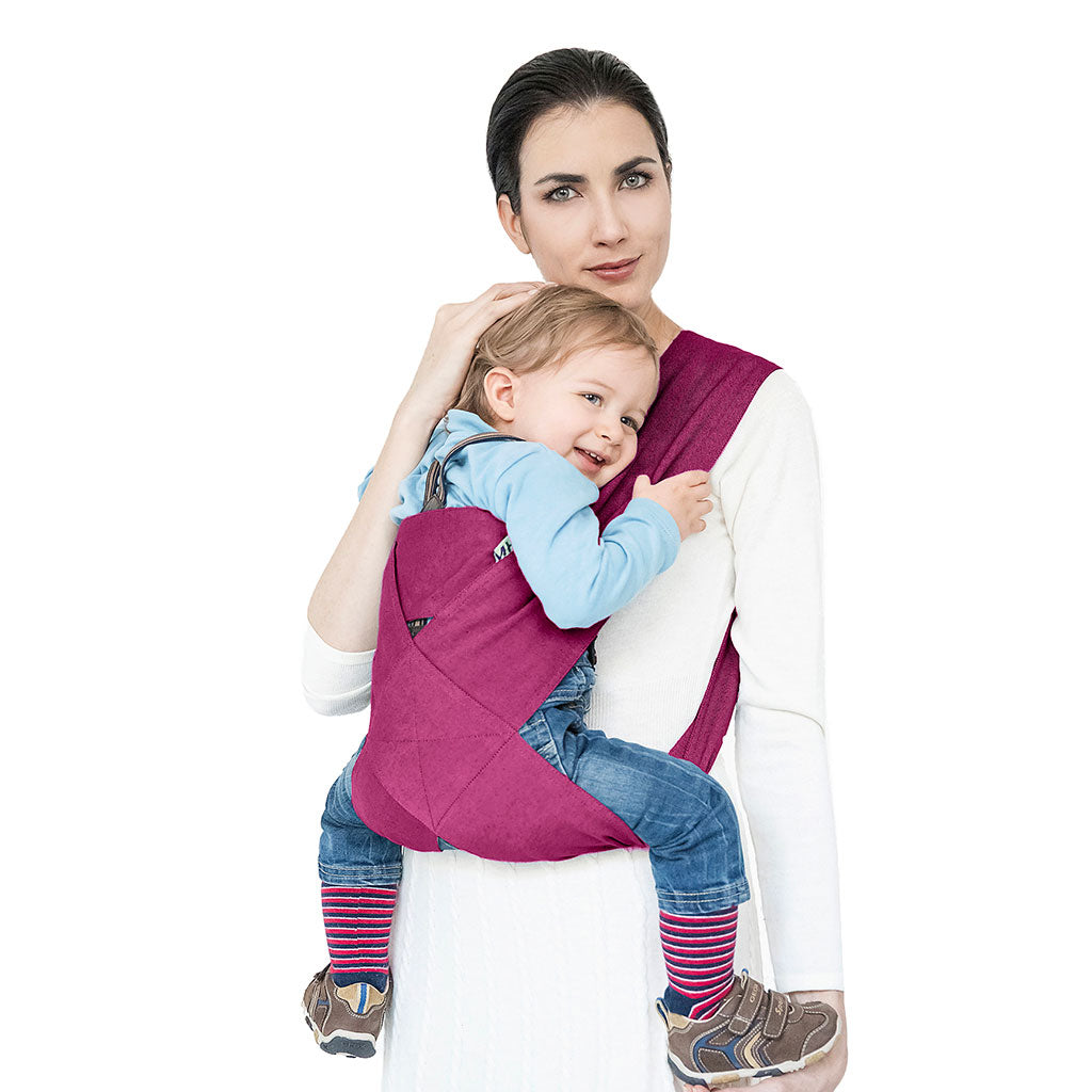 Portabebè Mhug Travel St. Moritz colore Fucsia si indossa in un solo gesto come una T-shirt indossato da modella con bambino di circa quattordici mesi correttamente seduto in posizione a m visione frontale di trequarti