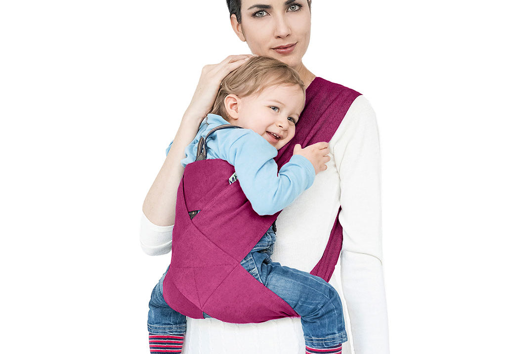 Portabebè Mhug Travel St. Moritz colore Fucsia si indossa in un solo gesto come una T-shirt indossato da modella con bambino di circa quattordici mesi correttamente seduto in posizione a m visione frontale di trequarti