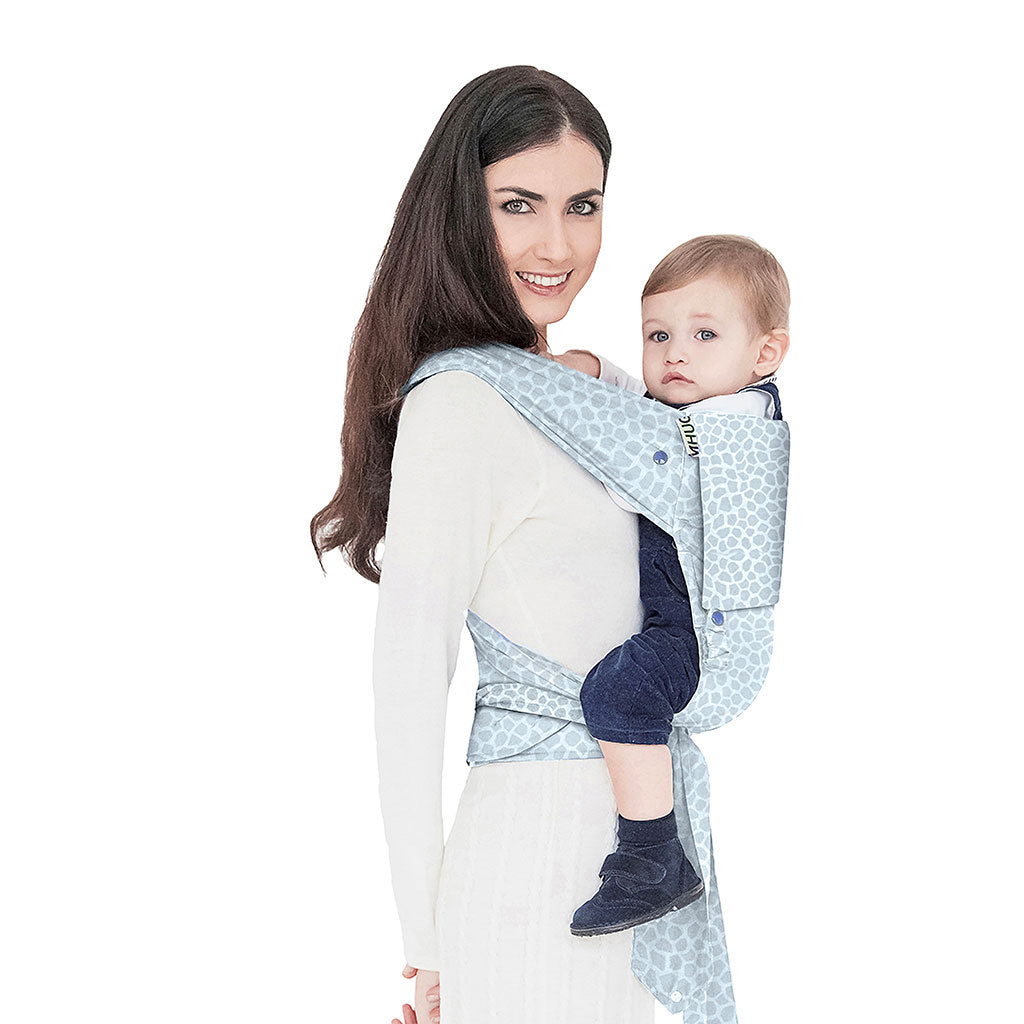 portabebè mhug mei tai collezione fantasia modello total Jungle fondo di base e bavero in fantasia animalier bianco e azzurro bottoni a pressione bianchi indossato da modella con bambino di dodici mesi circa in posizione canguro in ripresa trequarti