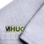 Dettaglio con logo Mhug di copertina in lana merino di colore carta da zucchero chiaro
